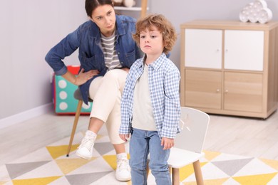 Photo of Resentful little boy and his mother arguing at home