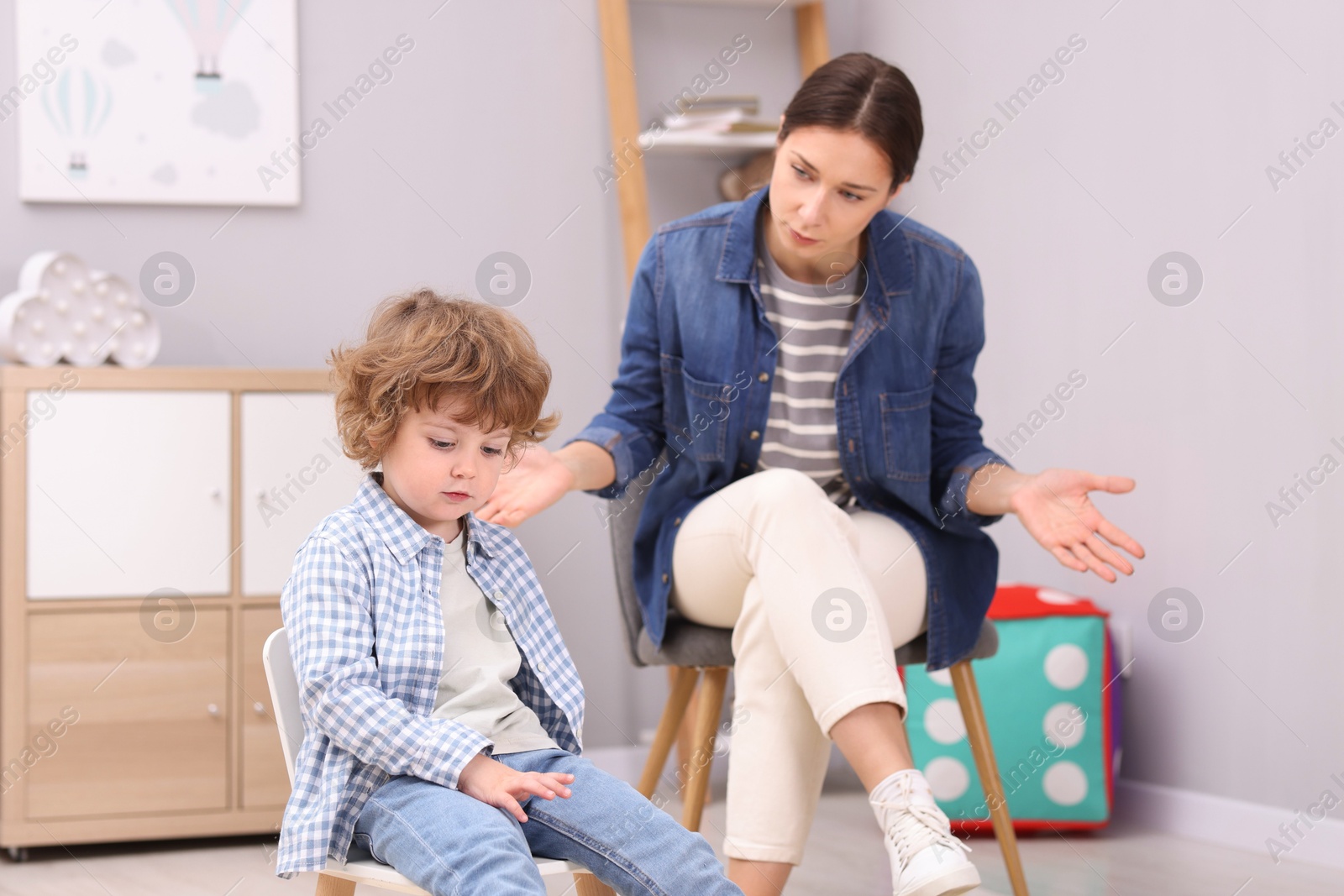 Photo of Resentful little boy and his mother arguing at home