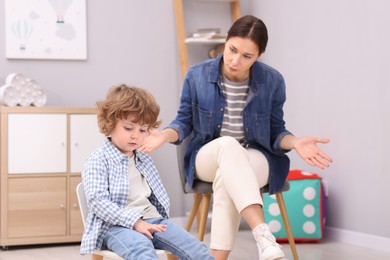 Photo of Resentful little boy and his mother arguing at home