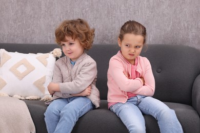 Photo of Resentful little brother and sister on couch at home. Family dispute