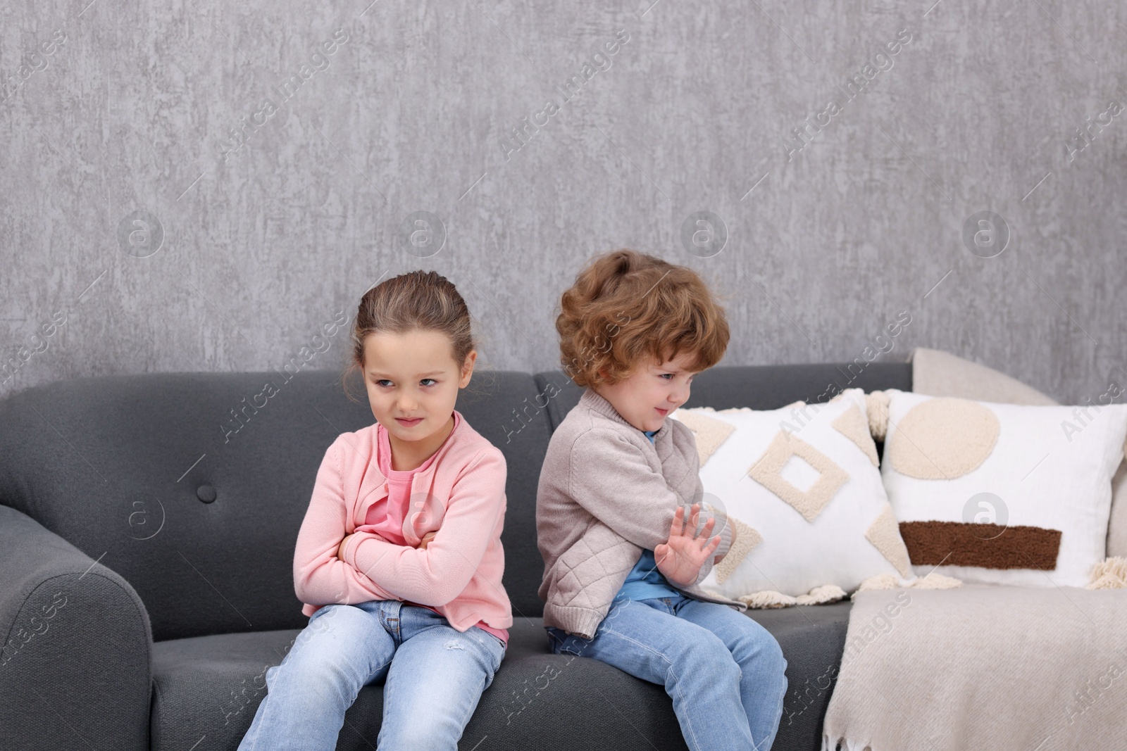 Photo of Resentful little brother and sister on couch at home. Family dispute