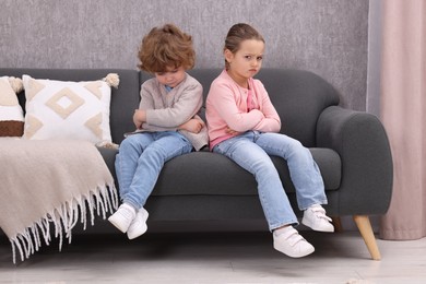 Photo of Resentful little brother and sister on couch at home. Family dispute