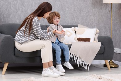 Photo of Resentful little boy and his mother arguing at home