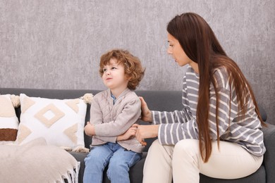 Photo of Resentful little boy and his mother arguing at home