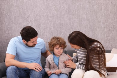 Photo of Resentful little boy and his parents arguing at home