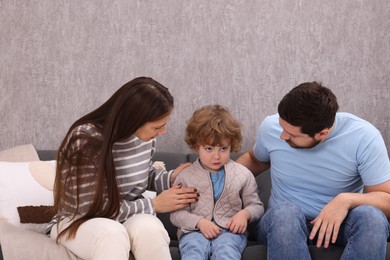 Photo of Resentful little boy and his parents arguing at home