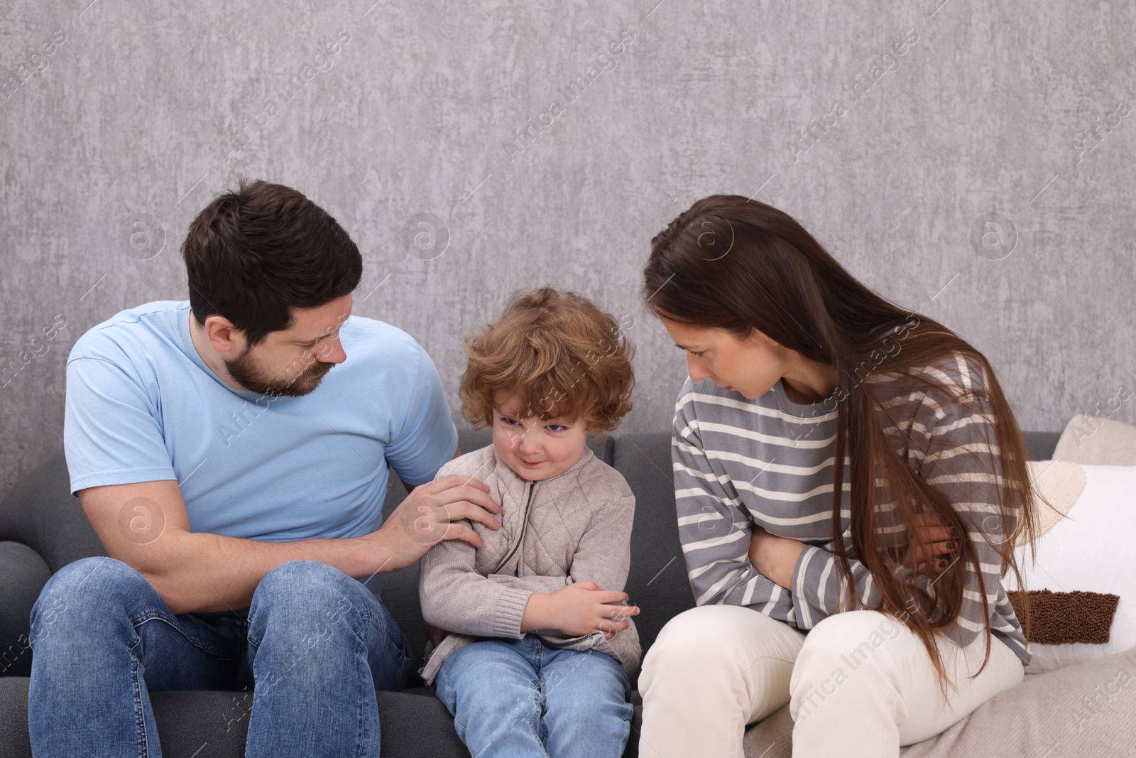 Photo of Resentful little boy and his parents arguing at home