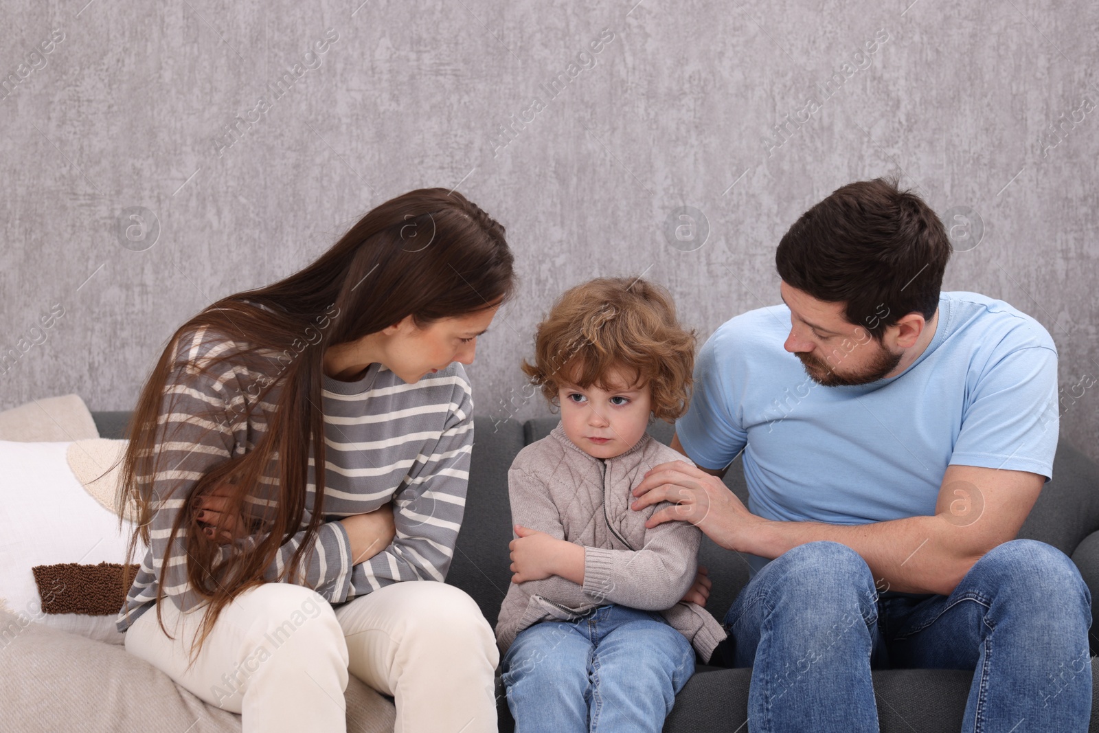 Photo of Resentful little boy and his parents arguing at home