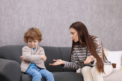 Photo of Resentful little boy and his mother arguing at home