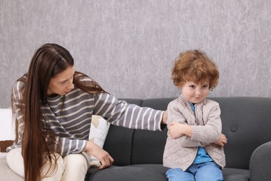 Photo of Resentful little boy and his mother arguing at home