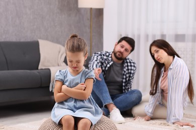 Photo of Resentful little girl and her parents at home. Family dispute