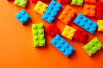 Photo of Construction toy. Colorful building bricks on orange background, flat lay