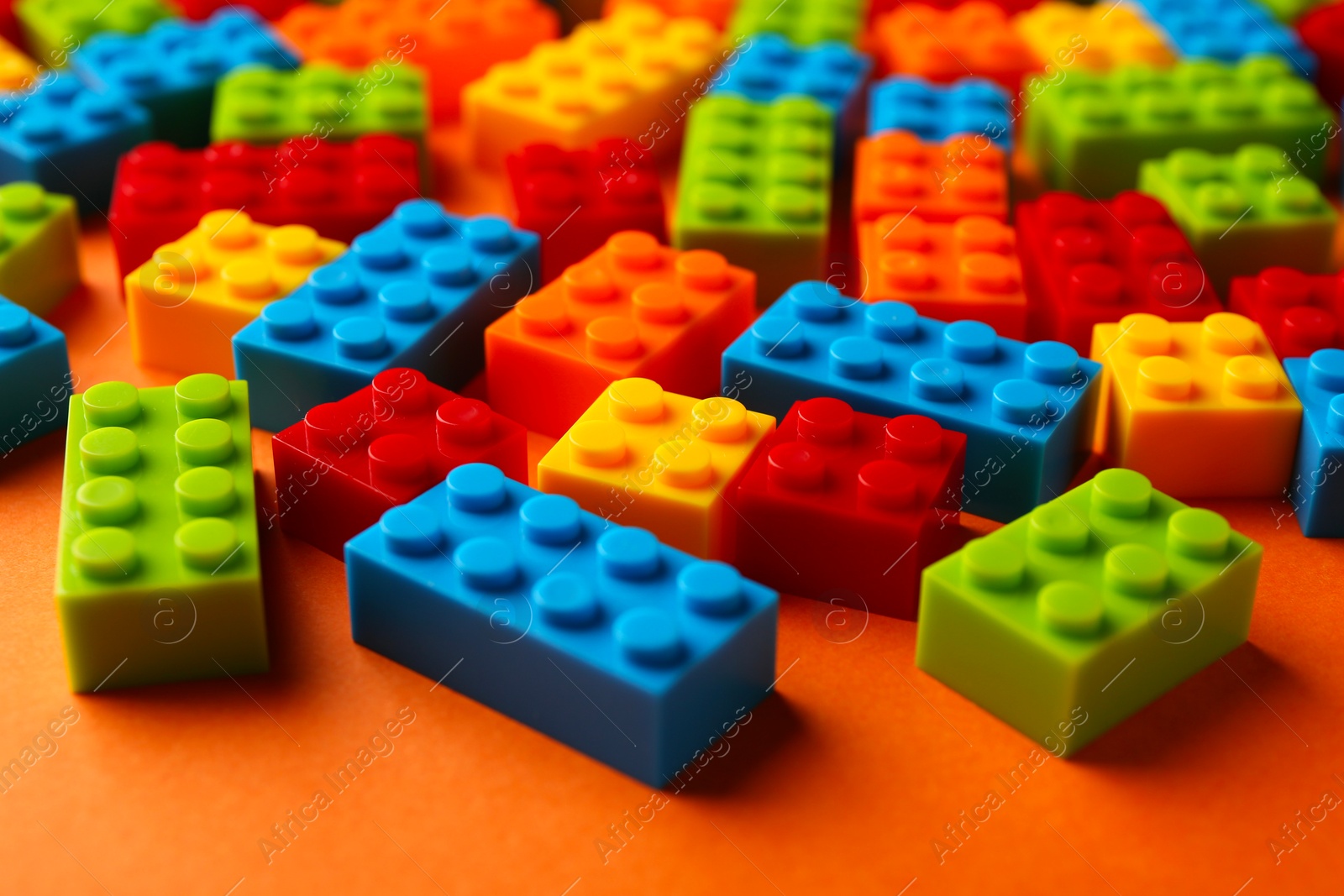 Photo of Construction toy. Colorful building bricks on orange background, closeup