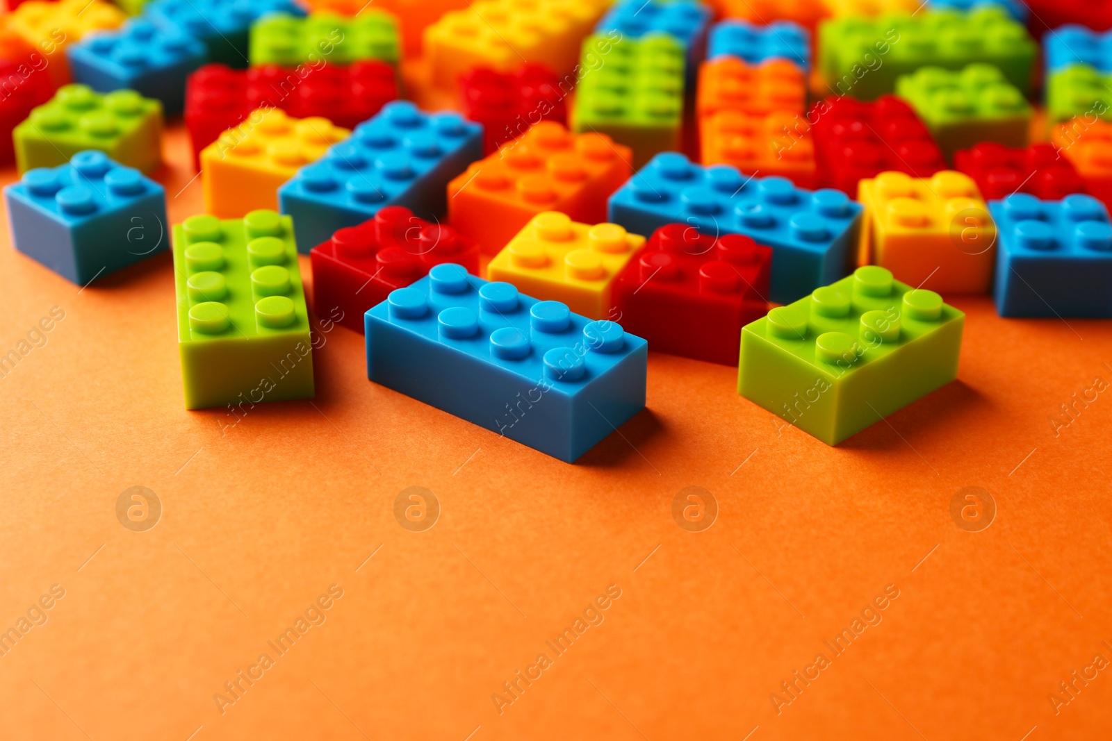 Photo of Construction toy. Colorful building bricks on orange background, closeup