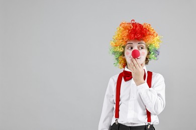 Photo of Cute little boy in clown wig and red nose on grey background, space for text. Surprise party