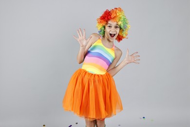 Photo of Happy girl dressed like clown on grey background. Surprise party