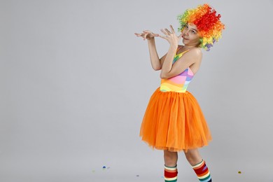 Photo of Cute girl dressed like clown on grey background, space for text. Surprise party