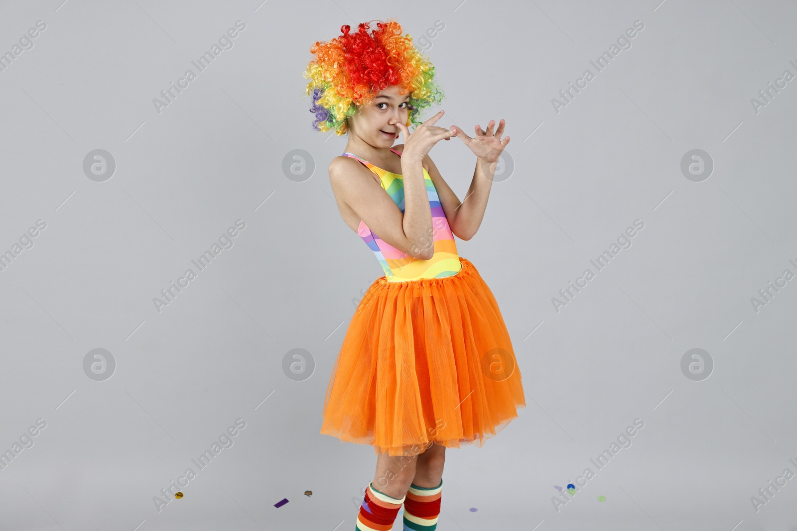 Photo of Cute girl dressed like clown on grey background, space for text. Surprise party