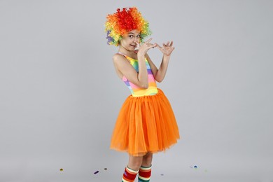 Photo of Cute girl dressed like clown on grey background, space for text. Surprise party