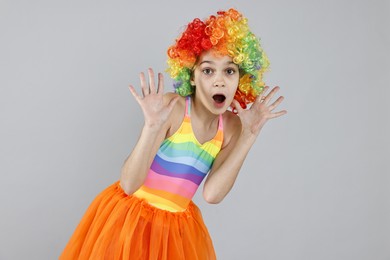 Photo of Emotional girl dressed like clown on grey background. Surprise party