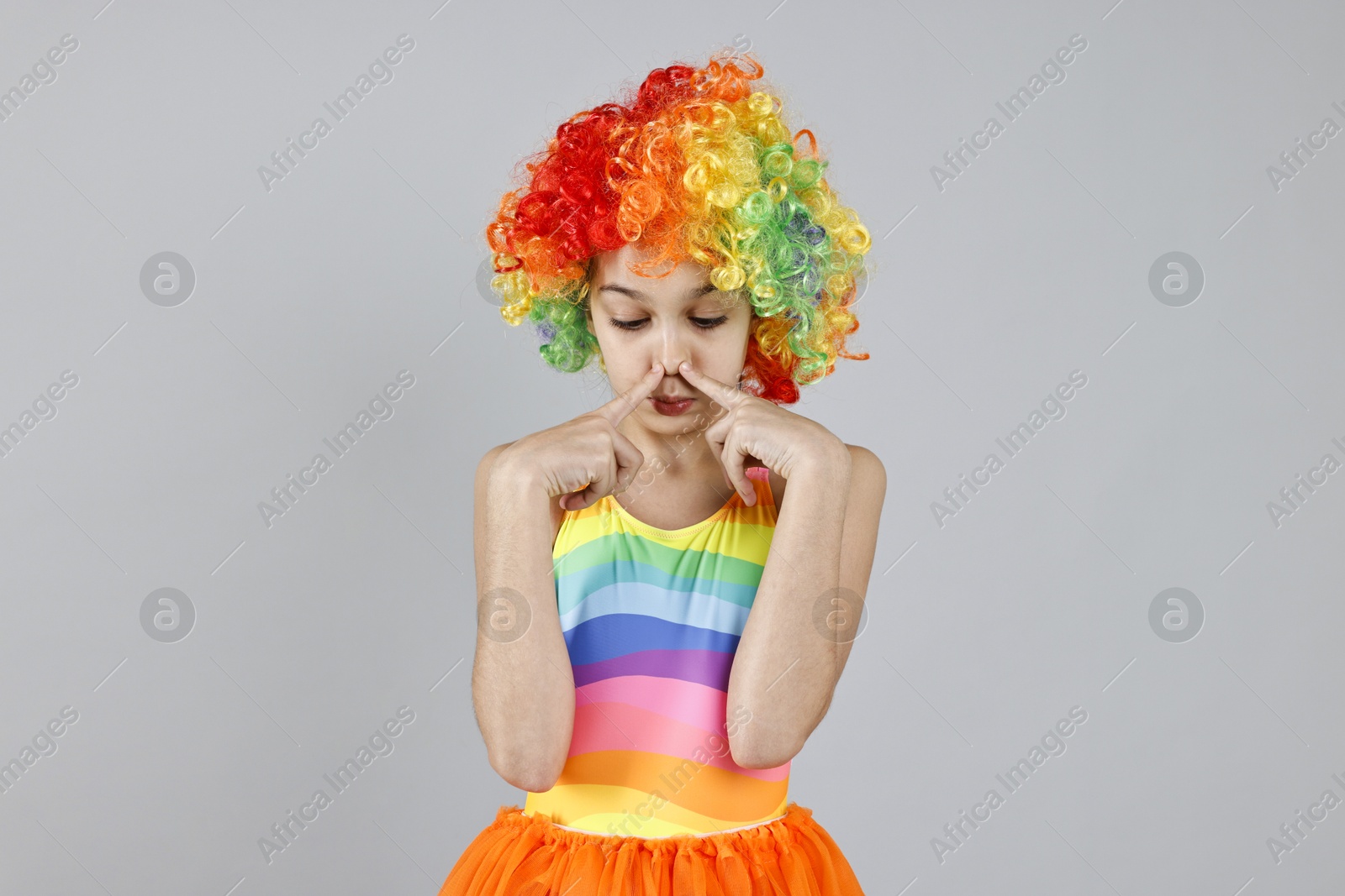 Photo of Cute girl dressed like clown on grey background. Surprise party