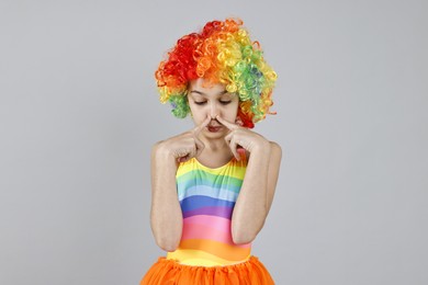 Photo of Cute girl dressed like clown on grey background. Surprise party