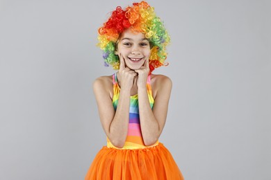 Photo of Happy girl dressed like clown on grey background. Surprise party