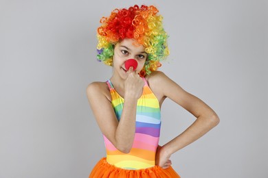 Photo of Cute girl dressed like clown on grey background. Surprise party