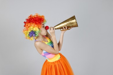 Photo of Girl dressed like clown with megaphone on grey background. Surprise party