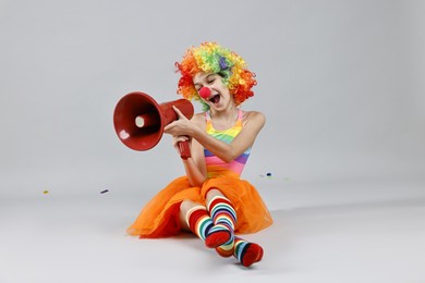 Photo of Girl dressed like clown shouting in megaphone on grey background. Surprise party