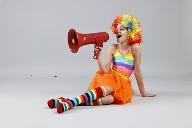 Photo of Girl dressed like clown shouting in megaphone on grey background. Surprise party