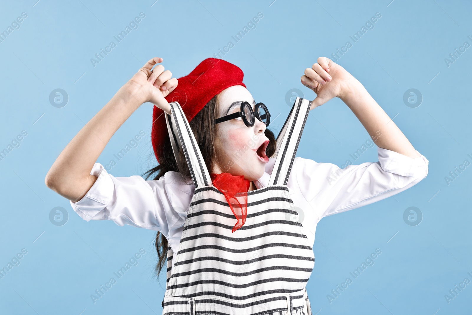 Photo of Emotional girl dressed like mime on light blue background. Surprise party