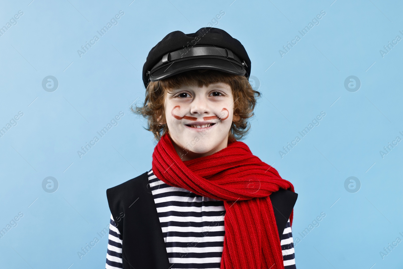 Photo of Smiling boy in mime costume on light blue background. Surprise party