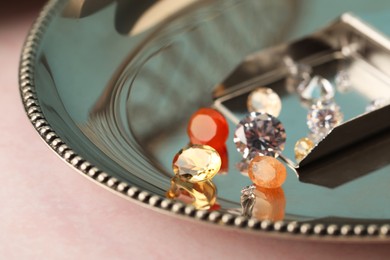 Photo of Tray with beautiful gemstones on light pink table, closeup