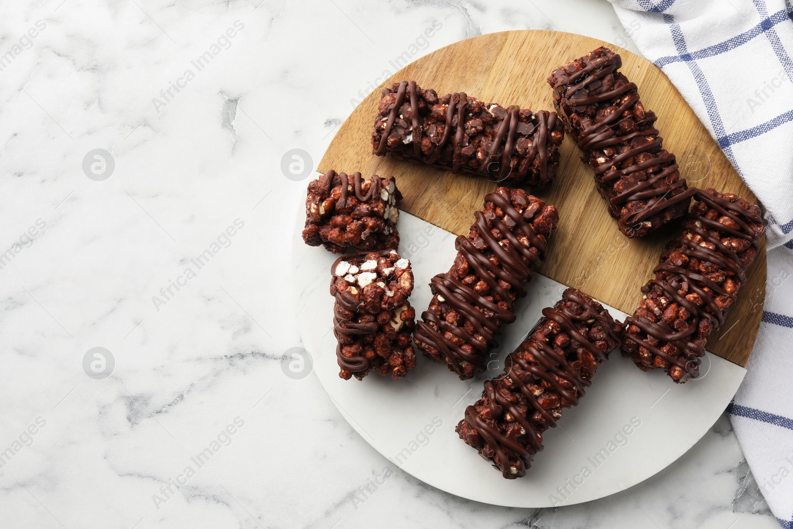 Photo of Delicious chocolate puffed rice bars on white marble table, top view. Space for text