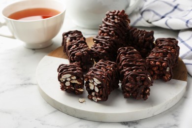 Photo of Delicious chocolate puffed rice bars on white marble table, closeup