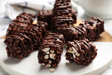 Photo of Delicious chocolate puffed rice bars on white marble table, closeup