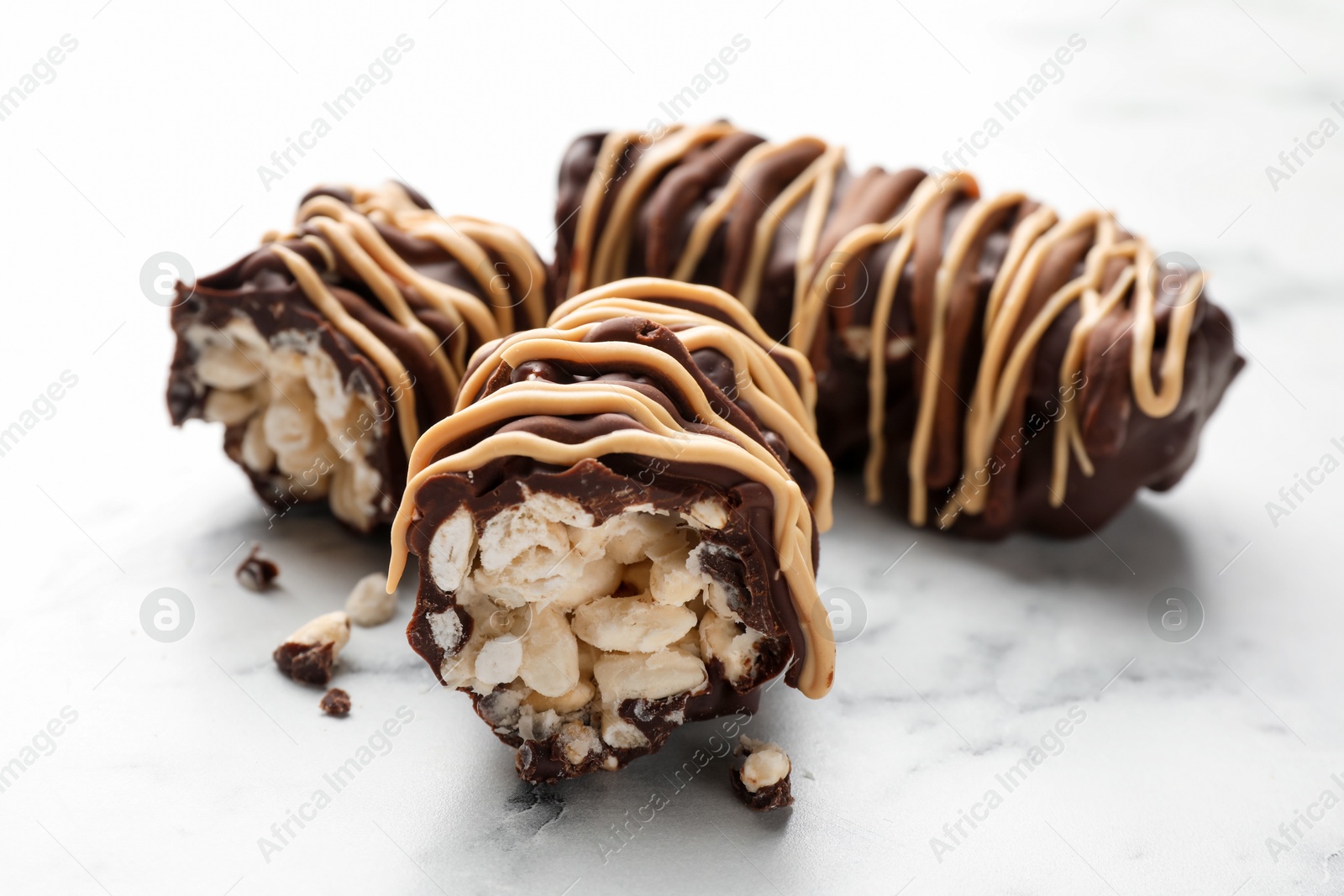 Photo of Delicious chocolate puffed rice bars on white marble table, closeup