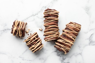 Photo of Delicious chocolate puffed rice bars on white marble table, flat lay