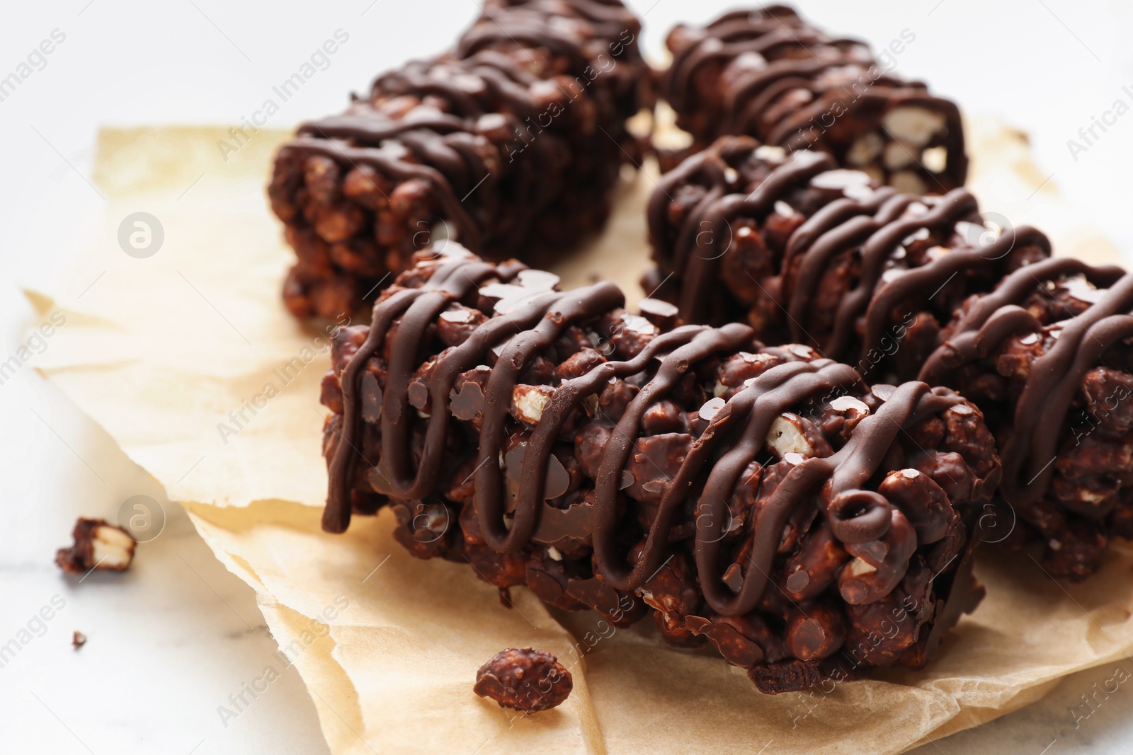 Photo of Delicious chocolate puffed rice bars on white marble table, closeup