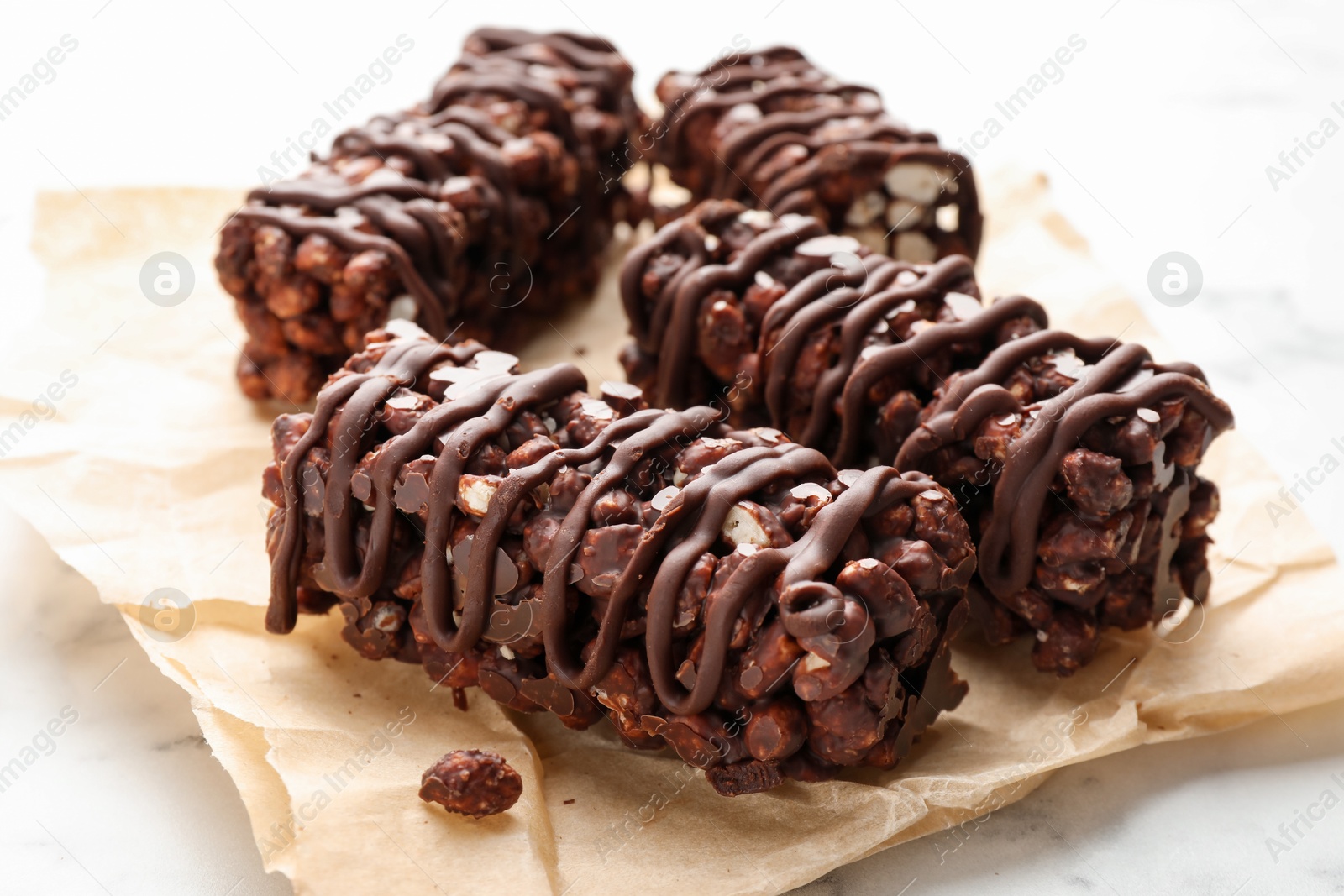 Photo of Delicious chocolate puffed rice bars on white marble table, closeup