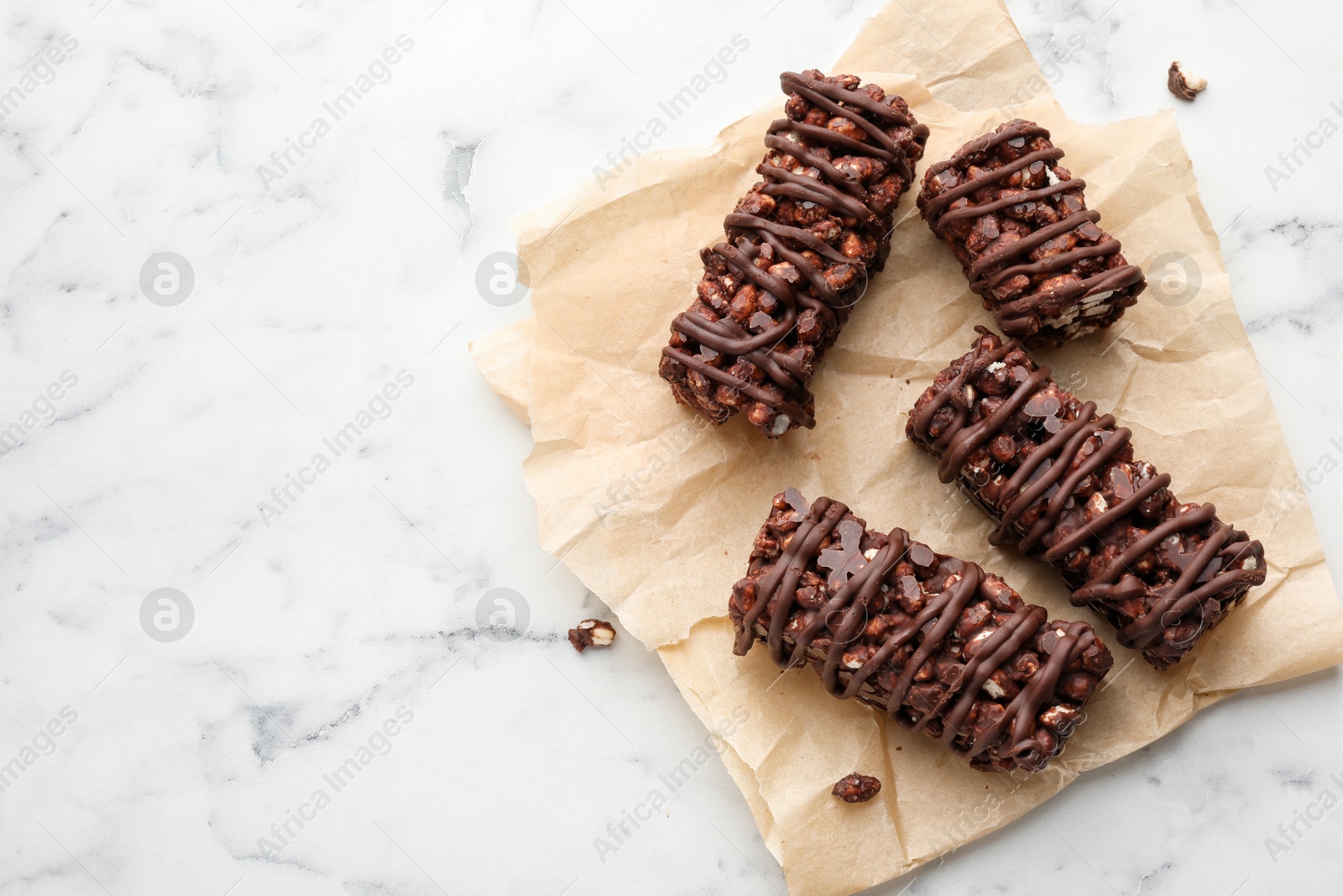 Photo of Delicious chocolate puffed rice bars on white marble table, top view. Space for text