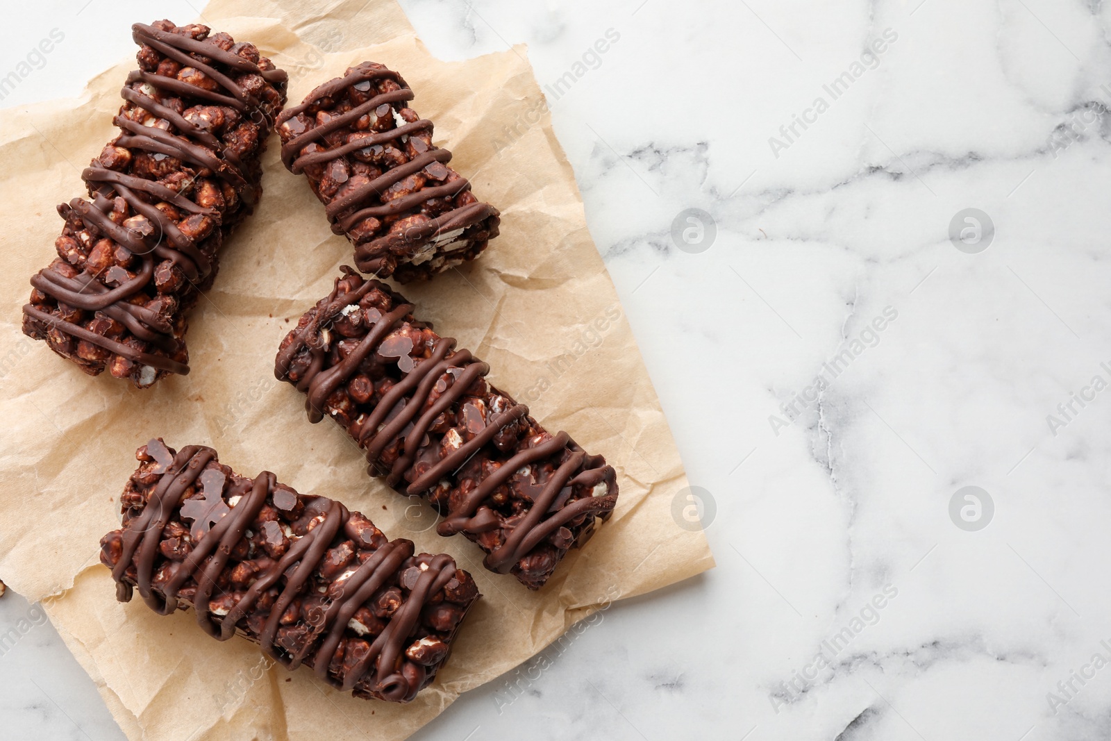 Photo of Delicious chocolate puffed rice bars on white marble table, top view. Space for text