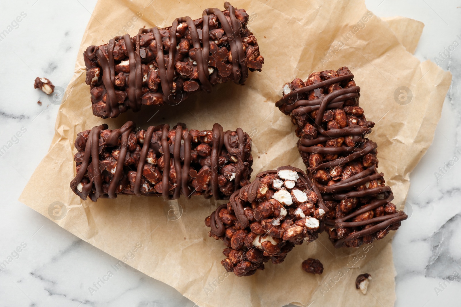 Photo of Delicious chocolate puffed rice bars on white marble table, top view