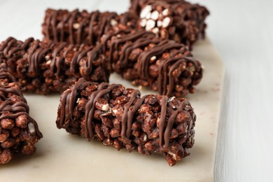 Photo of Delicious chocolate puffed rice bars on white wooden table, closeup