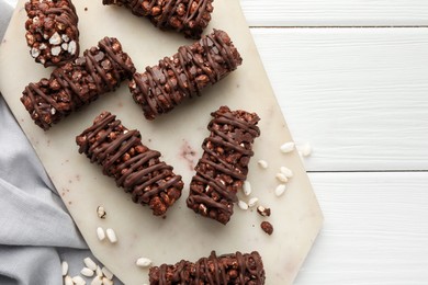 Photo of Delicious chocolate puffed rice bars on white wooden table, top view. Space for text