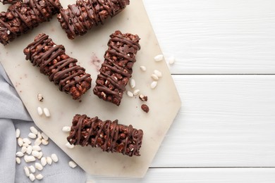 Photo of Delicious chocolate puffed rice bars on white wooden table, top view. Space for text