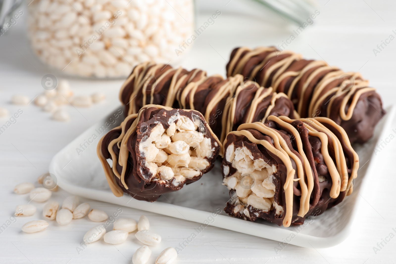 Photo of Delicious chocolate puffed rice bars on white wooden table, closeup