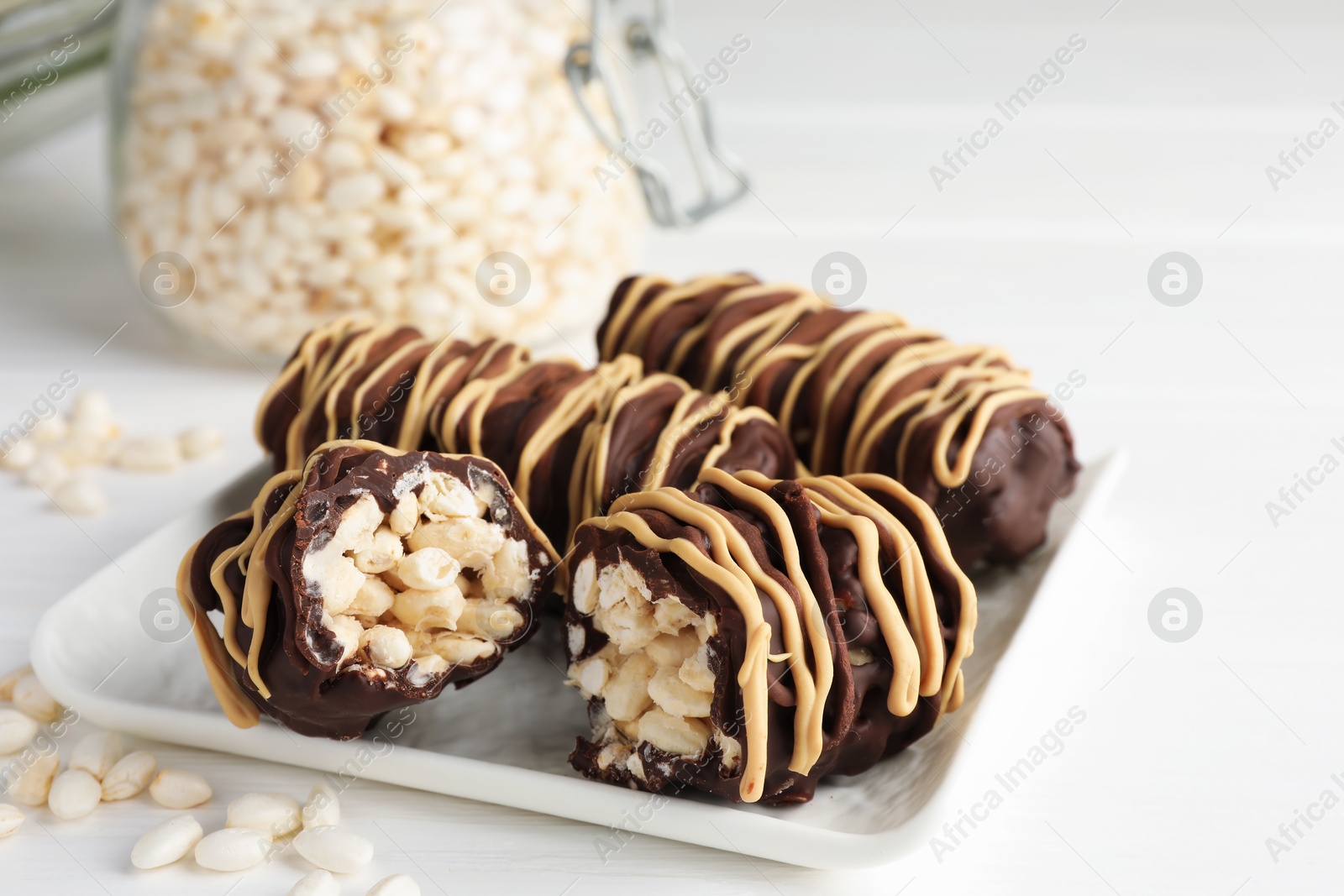 Photo of Delicious chocolate puffed rice bars on white wooden table, closeup