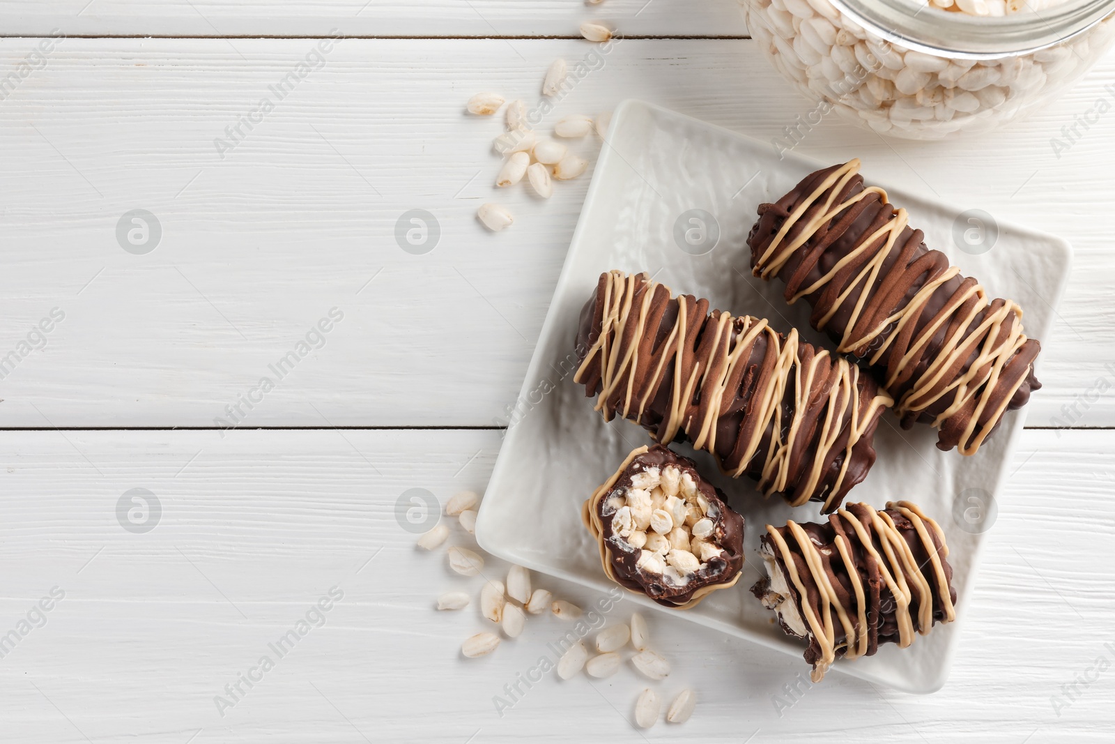 Photo of Delicious chocolate puffed rice bars on white wooden table, flat lay. Space for text